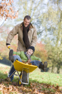 Father giving son ride in wheelbarrowe through autumn leaves